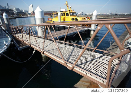 横浜港の浮桟橋へと続く連絡通路と黄色の船 135707869