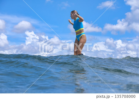 Athletic Female Athlete Standing Firmly Amid Crashing Surf Under Summer Sky 135708000