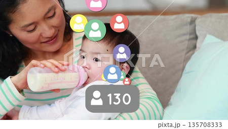 Feeding father holding Chinese baby with pink bottle in living room with user-icon count overlay 135708333