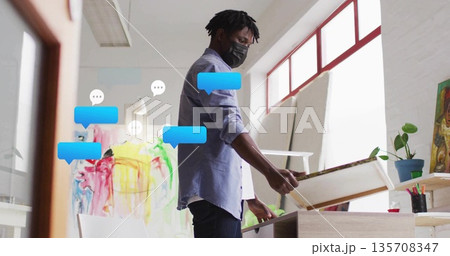Holding blank canvas artist wearing mask working in art studio, with easel and art supplies 135708347