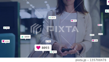 Standing businesswoman in blazer holding smartphone and handbag in lobby, showing reaction icons Standing businesswoman in blazer holding smartphone and handbag in lobby, showing reaction icons 135708478