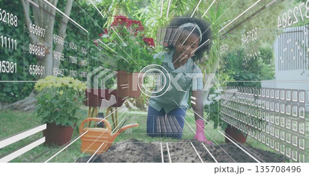Girl wearing apron kneeling and planting in raised bed in backyard, with watering can, trowel Girl wearing apron kneeling and planting in raised bed in backyard, with watering can, trowel 135708496