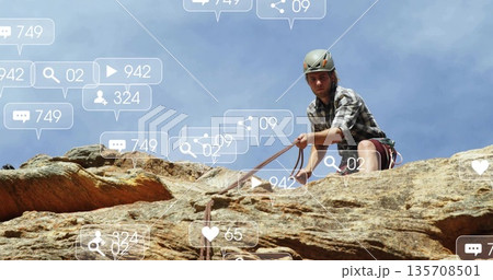 Scaling climber wearing helmet harness rope on sandstone face with floating icons, copy space Scaling climber wearing helmet harness rope on sandstone face with floating icons, copy space 135708501