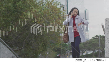 Descending businesswoman carrying brown bag, using smartphone, checking watch in plaza, copy space Descending businesswoman carrying brown bag, using smartphone, checking watch in plaza, copy space 135708677