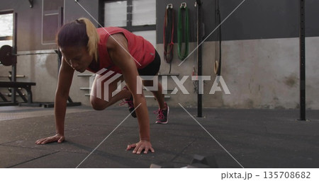 African American woman wearing sportswear performing mountain climber exercise on rubber gym floor 135708682