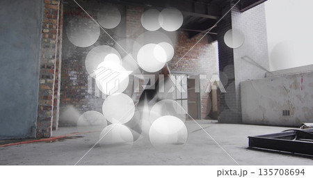 Jumping male dancer wearing sleeveless top dark pants in warehouse loft with exposed brick red cord Jumping male dancer wearing sleeveless top dark pants in warehouse loft with exposed brick red cord 135708694