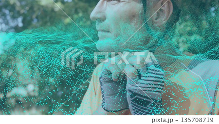 Securing bicycle helmet, cyclist in park wearing fingerless gloves and athletic shirt, copy space Securing bicycle helmet, cyclist in park wearing fingerless gloves and athletic shirt, copy space 135708719