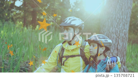 Standing couple of cyclists wearing jackets in forest clearing, with helmets and hydration packs 135708721