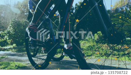Pedaling friends' legs powering through park trail, with bicycles, leggings, gold star overlay Pedaling friends' legs powering through park trail, with bicycles, leggings, gold star overlay 135708722