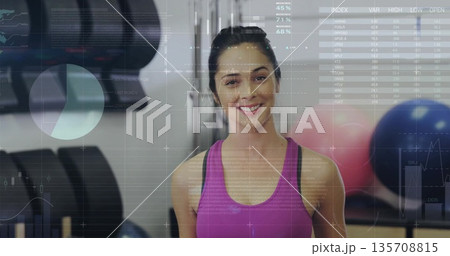 Tracking athletic woman wearing bright pink sports top lifting dumbbell in gym, with data overlay Tracking athletic woman wearing bright pink sports top lifting dumbbell in gym, with data overlay 135708815
