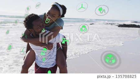 Carrying couple wrapping arms on sandy beach by ocean, featuring green environmental icons Carrying couple wrapping arms on sandy beach by ocean, featuring green environmental icons 135708825