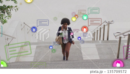 Walking executive carrying tote bag talking on smartphone climbing stone steps showing alerts 135709572