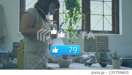 Pouring ceramic artist wearing apron glazing bowl at studio, with chalkboard sign, copy space Pouring ceramic artist wearing apron glazing bowl at studio, with chalkboard sign, copy space 135709603