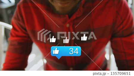 Sitting adult man wearing red-black plaid shirt showing thumbs-up icons plus notification in cafe Sitting adult man wearing red-black plaid shirt showing thumbs-up icons plus notification in cafe 135709651
