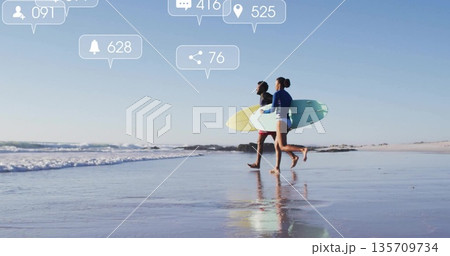 Sprinting surfers in rash guard and shorts carrying boards at beach, with social icons, copy space 135709734