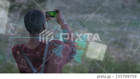 Woman wearing maroon sweater carrying crossbody bag capturing hillside with smartphone and overlays 135709759
