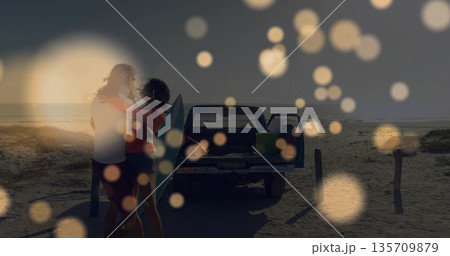 Hugging couple watching sunset on sandy shoreline, with pickup truck and surfboard, copy space Hugging couple watching sunset on sandy shoreline, with pickup truck and surfboard, copy space 135709879