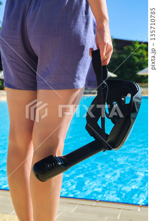 Close-Up of a Woman Holding a Snorkeling Mask Against the Background of a Sparkling Pool, Ready for an Exciting Underwater Adventure Close-Up of a Woman Holding a Snorkeling Mask Against the Background of a Sparkling Pool, Ready for an Exciting Underwater Adventure 135710785