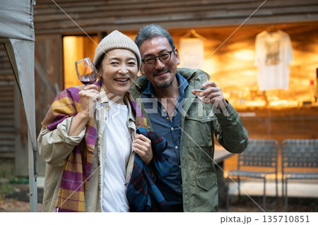 焚き火を前にキャンプを楽しむシニアカップル 135710851