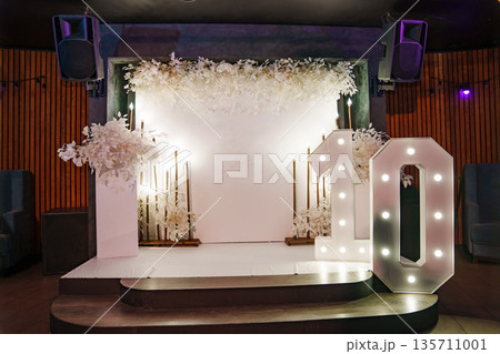 a white wall and a column with flowers, and a large number ten with light bulbs. a white wall and a column with flowers, and a large number ten with light bulbs. 135711001