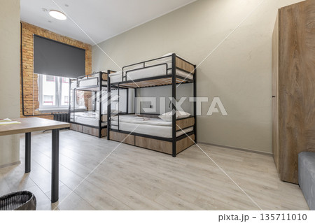 Hostel dormitory room with black bunk beds and exposed brick wall 135711010