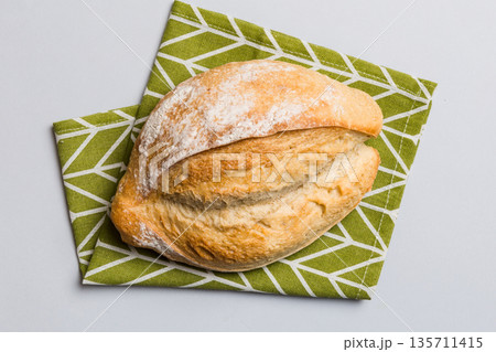 Freshly baked delicious french bread with napkin on rustic table top view. Healthy white bread loaf 135711415