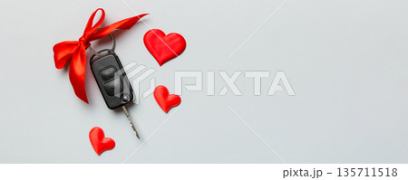 Car key with a red bow and a heart on Colored table. Giving present or gift for valentine day or christmas, Top view with copy space 135711518