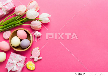 Easter frame with eggs, gift box and tulip on a colored background. The minimal concept. Top view Happy Easter composition. Card with a copy space of the place for the text 135711725