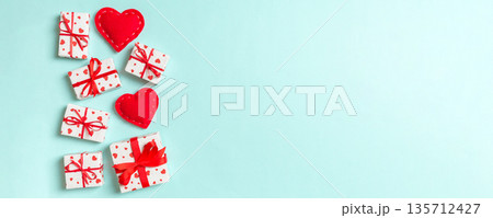 Holiday composition of gift boxes and red textile hearts on colorful background with empty space for your design. Top view of Valentine's Day concept Holiday composition of gift boxes and red textile hearts on colorful background with empty space for your design. Top view of Valentine's Day concept 135712427