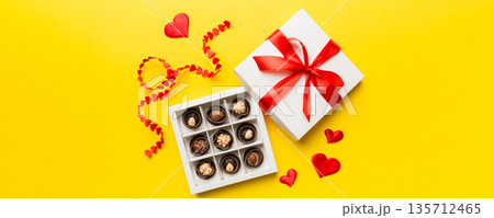 Delicious chocolate pralines in red box for Valentine's Day. Heart shaped box of chocolates top view with copy space 135712465