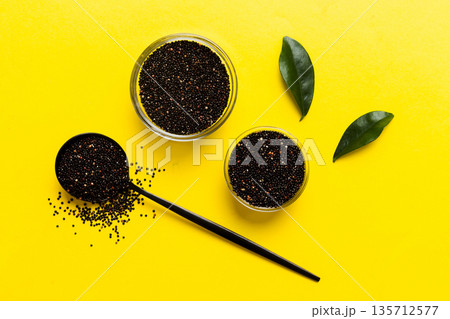 quinoa seeds in bowl and spoon on colored background. Healthy kinwa in small bowl. Healthy superfood quinoa seeds in bowl and spoon on colored background. Healthy kinwa in small bowl. Healthy superfood 135712577