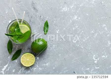 Caipirinha, Mojito cocktail, vodka or soda drink with lime, mint and straw on table background. Refreshing beverage with mint and lime in glass top view flat lay Caipirinha, Mojito cocktail, vodka or soda drink with lime, mint and straw on table background. Refreshing beverage with mint and lime in glass top view flat lay 135712594
