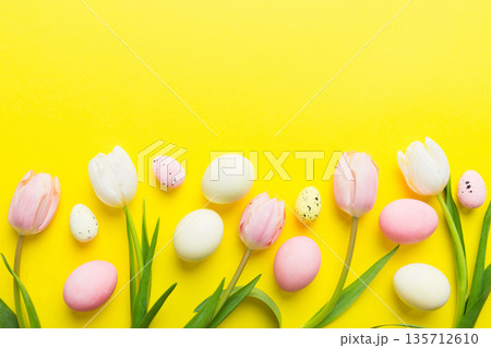 Happy Easter composition. Easter eggs on colored table with yellow Tulips. Natural dyed colorful eggs background top view with copy space 135712610