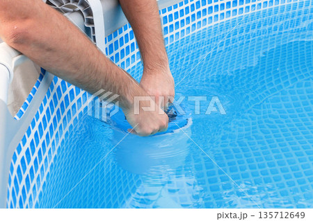 Man cleans skimmer for the frame pool. Contaminated pool cleaning concept 135712649