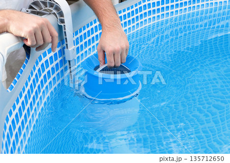 Man cleans skimmer for the frame pool. Contaminated pool cleaning concept Man cleans skimmer for the frame pool. Contaminated pool cleaning concept 135712650