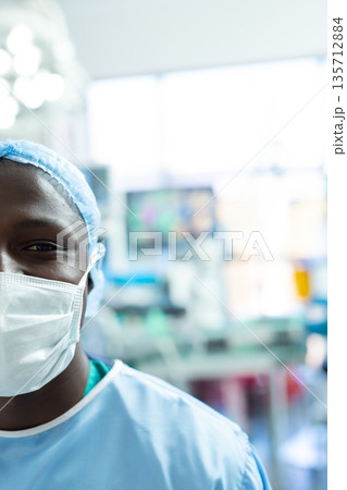 African American male surgeon wearing scrubs, mask checking display in operating room, copy space African American male surgeon wearing scrubs, mask checking display in operating room, copy space 135712884