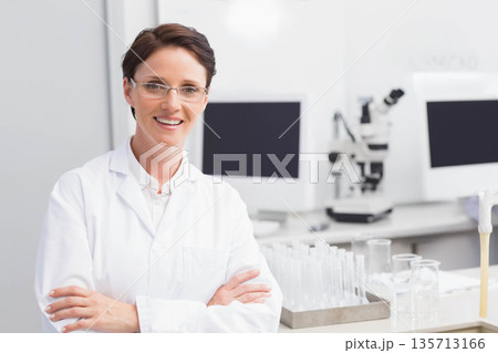 Mid adult woman scientist standing at lab bench with microscope and test tubes, copy space 135713166