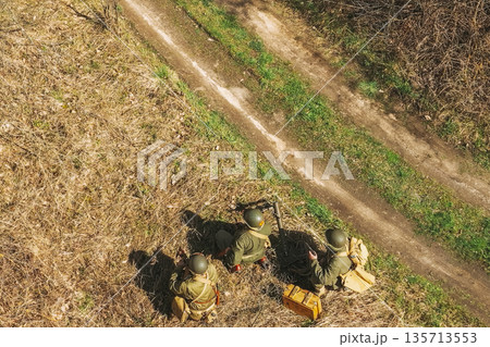 Men Dressed As US American Soldiers Of USA Infantry Of World War II sneaking around In spring Autumn Day. Soldiers prepare mortar for battle In dry grass. Aerial view elevated shot 135713553