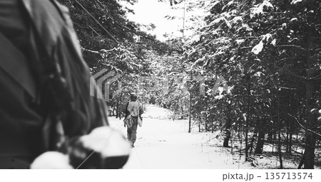 Usa Army Soldiers Of World War Ii. Heroes Of War. Re-enactors Dressed As American Infantry Soldier Marching Through Forest Road In Cold Winter Day. Group Of Usa Soldiers Marching Country Road Usa Army Soldiers Of World War Ii. Heroes Of War. Re-enactors Dressed As American Infantry Soldier Marching Through Forest Road In Cold Winter Day. Group Of Usa Soldiers Marching Country Road 135713574