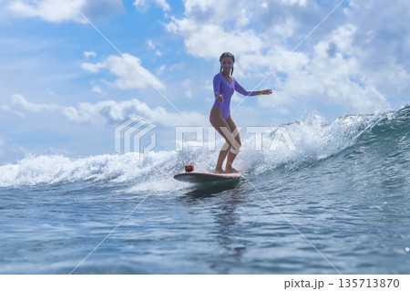 Energetic Woman Confidently Surfs Across Sunlit Blue Waters With Enthusiasm Energetic Woman Confidently Surfs Across Sunlit Blue Waters With Enthusiasm 135713870