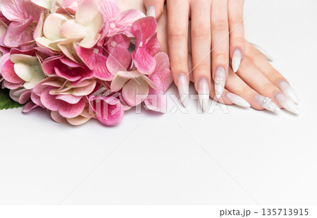 Woman showcasing elegant long almond nails with floral art 135713915