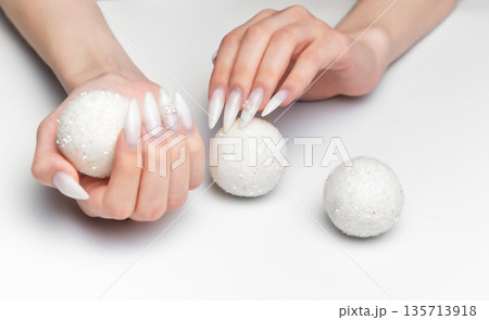 Woman hands holding sparkling christmas ornaments with long nails 135713918