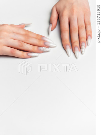 Woman's hands showing long white almond shape nails with art Woman's hands showing long white almond shape nails with art 135713919