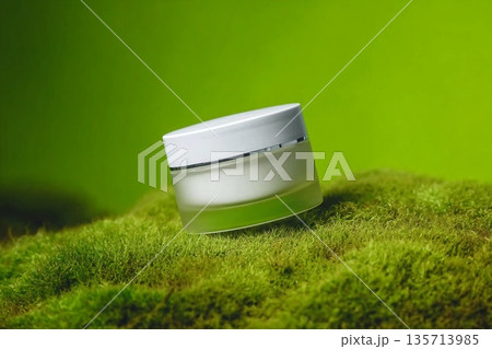 A jar of white beauty cream in a container on green background. Cosmetic package mockup. Skin cosmetic product. 135713985