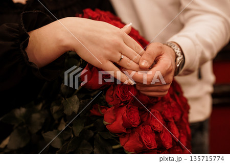 Romantic Proposal Moment with Diamond Ring and Red Roses Held by Loving Couple in Intimate Setting Romantic Proposal Moment with Diamond Ring and Red Roses Held by Loving Couple in Intimate Setting 135715774