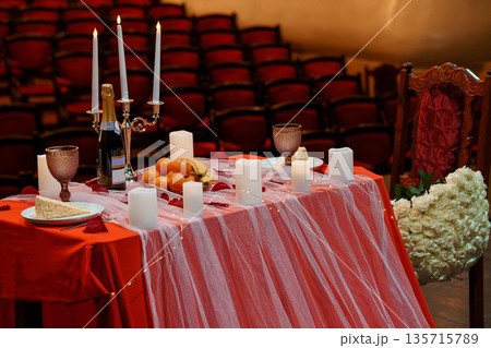 Romantic Red Table Setting with Candles, Champagne, and Flowers in an Elegant Auditorium Venue 135715789