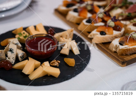 Gourmet Cheese Platter with Assorted Cheeses, Walnuts, Dried Fruits, and Jam on Black Slate Board Gourmet Cheese Platter with Assorted Cheeses, Walnuts, Dried Fruits, and Jam on Black Slate Board 135715819
