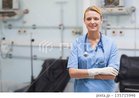 Female nurse standing with arms crossed wearing scrubs glove and stethoscope at clinic, copy space Female nurse standing with arms crossed wearing scrubs glove and stethoscope at clinic, copy space 135715946