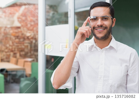 Man wearing white shirt and AR glasses standing by glass partition, touching device, copy space Man wearing white shirt and AR glasses standing by glass partition, touching device, copy space 135716082