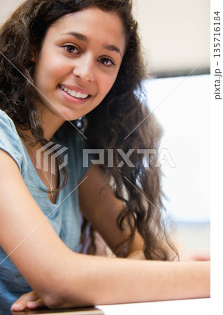 Female smiling and leaning on white tabletop at desk, wearing teal top and necklace Female smiling and leaning on white tabletop at desk, wearing teal top and necklace 135716184